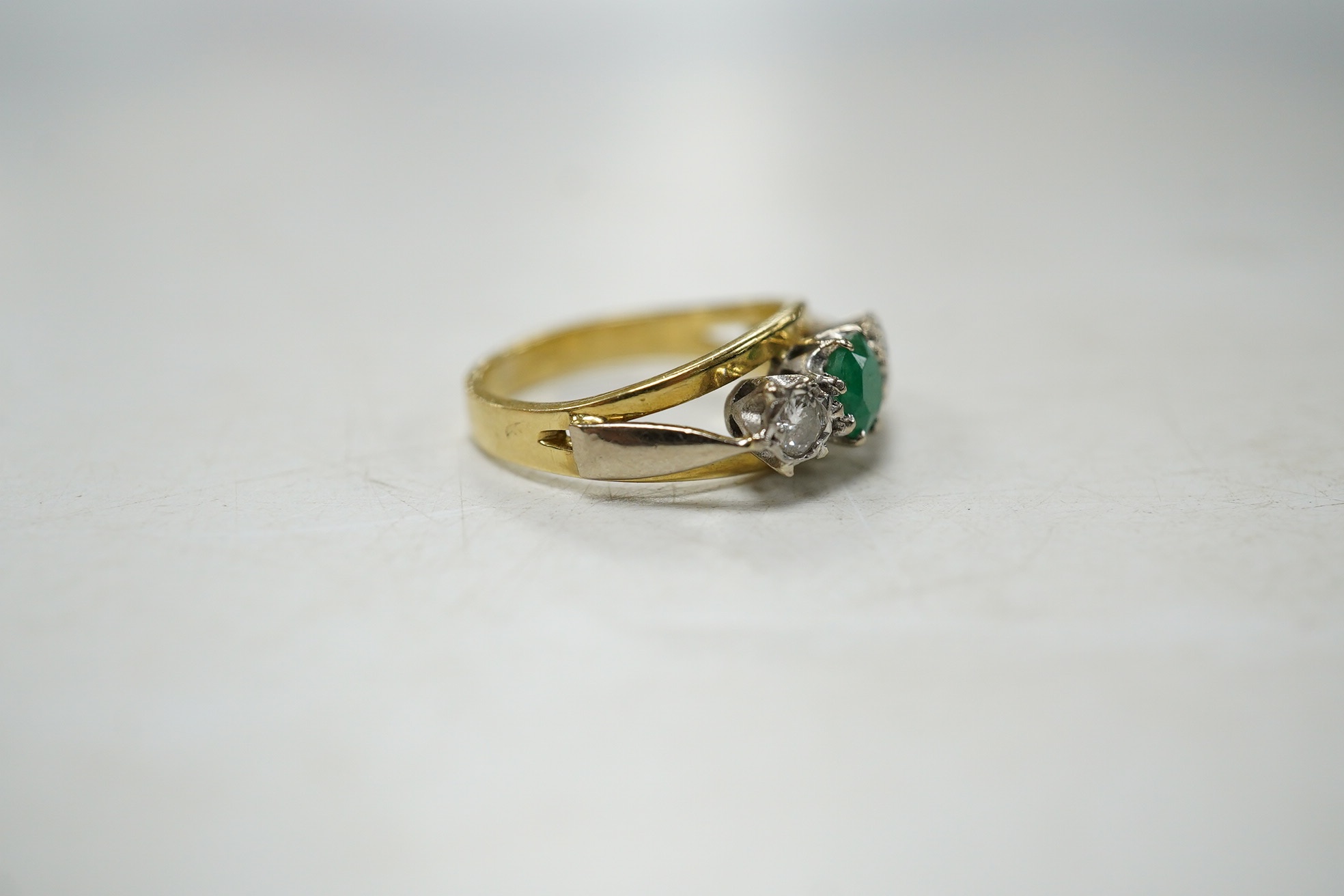 A modern yellow metal, emerald and diamond set three stone ring, size G, gross weight 3.8 grams. Condition - fair